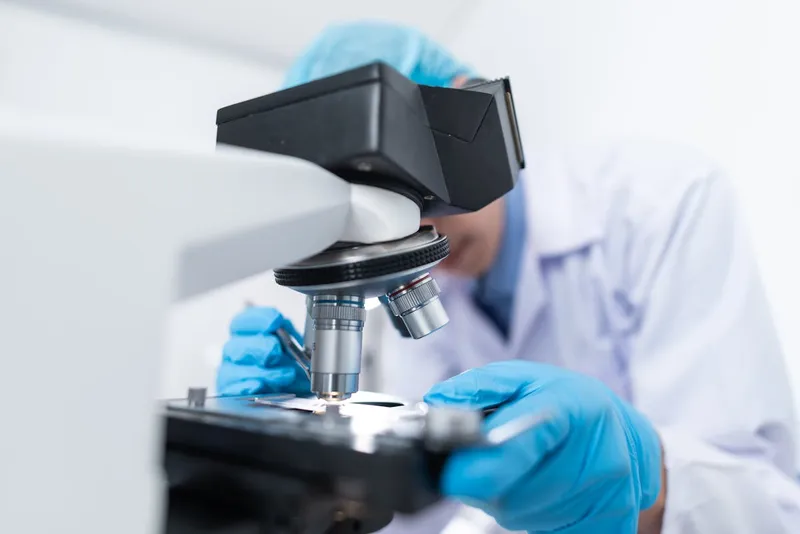 Especialista realizando análisis de agua con microscopio en laboratorio certificado